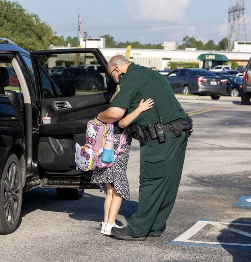 school resource officer hugging young girl outside school - donate to FASRO